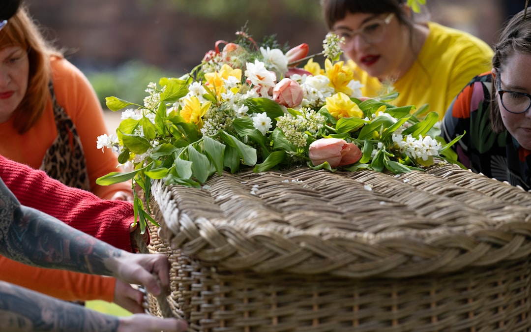People carrying a wicker coffin adorned with flowers outdoors.